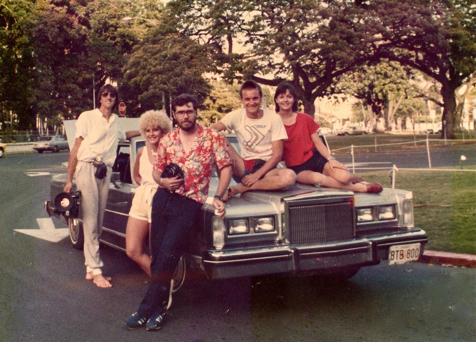 Five Wonder World crew members on a vintage car during an overseas shoot